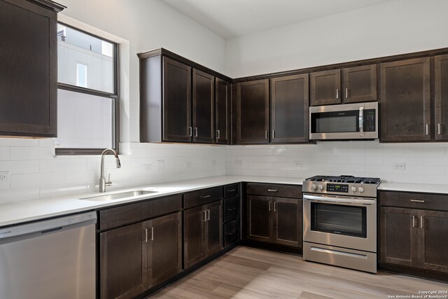 kitchen featuring sink, dark brown cabinetry, stainless steel appliances, and light hardwood / wood-style floors