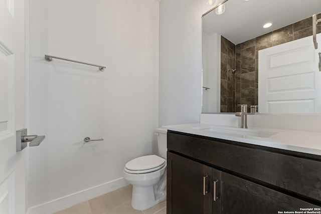 bathroom featuring vanity, toilet, a tile shower, and tile patterned flooring