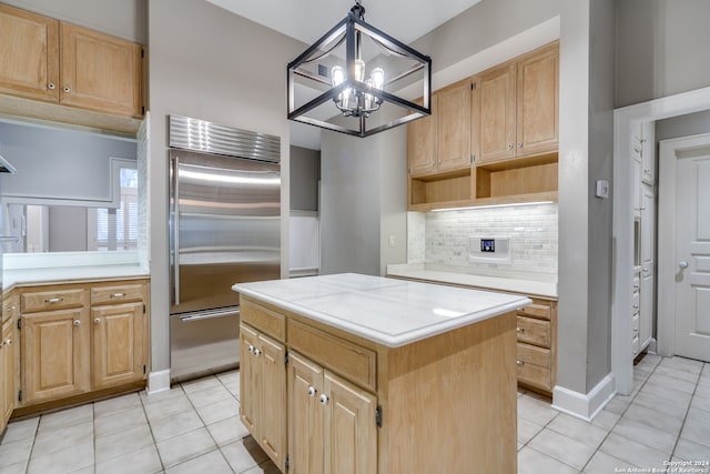 kitchen featuring stainless steel built in fridge, a kitchen island, hanging light fixtures, light tile patterned floors, and a chandelier