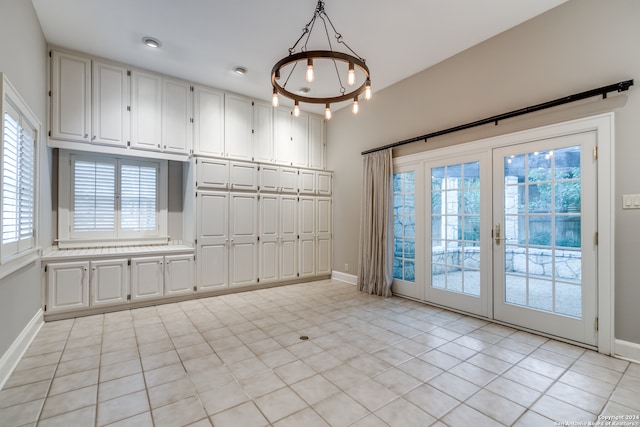 unfurnished dining area with a wealth of natural light, an inviting chandelier, and light tile patterned floors