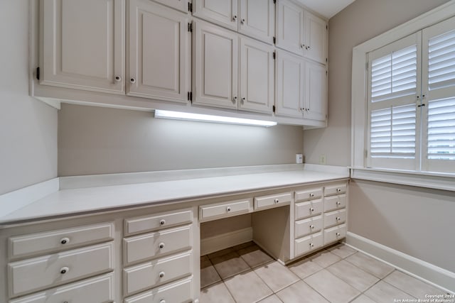 unfurnished office featuring built in desk and light tile patterned flooring