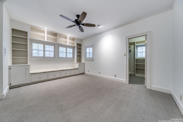 interior space with a healthy amount of sunlight, built in features, ornamental molding, and light colored carpet