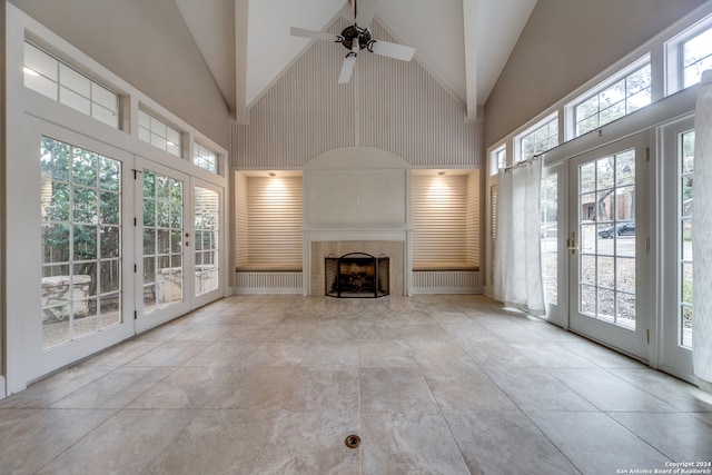 unfurnished living room featuring a tile fireplace, french doors, high vaulted ceiling, and ceiling fan