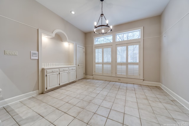 unfurnished dining area featuring a chandelier and light tile patterned flooring