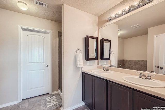 bathroom featuring vanity, walk in shower, a textured ceiling, and tile patterned flooring