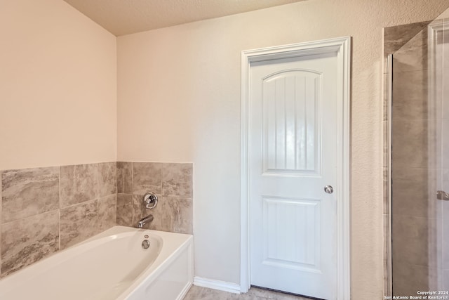 bathroom featuring a textured ceiling and independent shower and bath