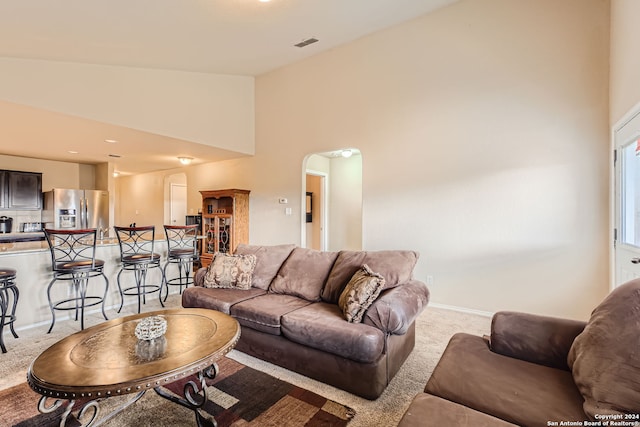 carpeted living room with high vaulted ceiling