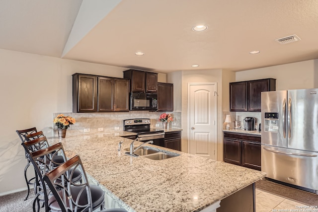 kitchen with light stone countertops, sink, appliances with stainless steel finishes, kitchen peninsula, and a breakfast bar