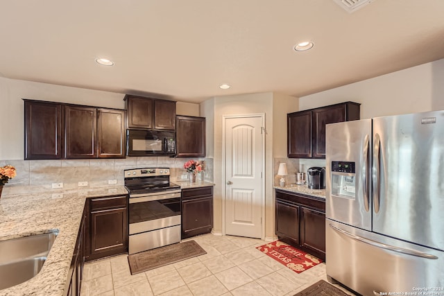 kitchen featuring stainless steel appliances, light stone countertops, dark brown cabinetry, and decorative backsplash