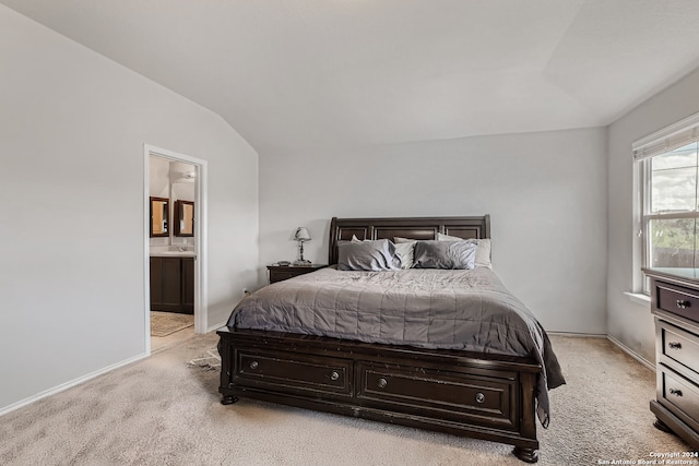 bedroom featuring ensuite bathroom, light colored carpet, sink, and vaulted ceiling