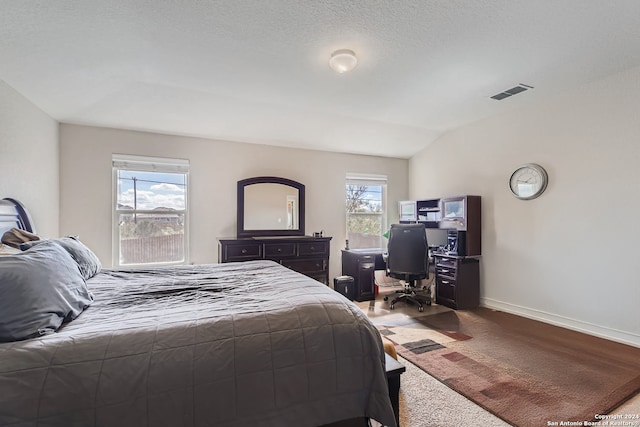 carpeted bedroom with lofted ceiling, a textured ceiling, and multiple windows