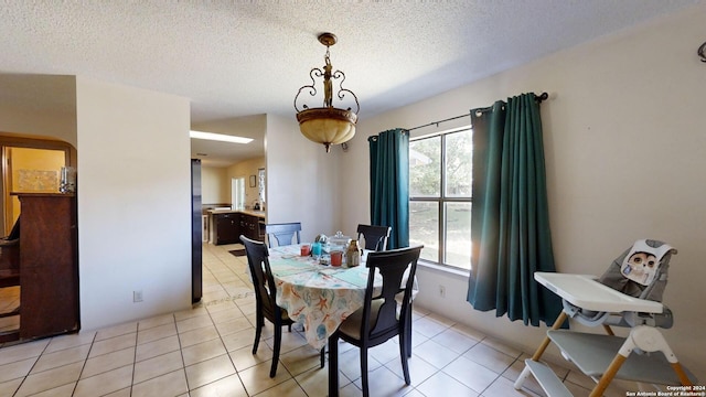 dining area featuring a textured ceiling and light tile patterned floors