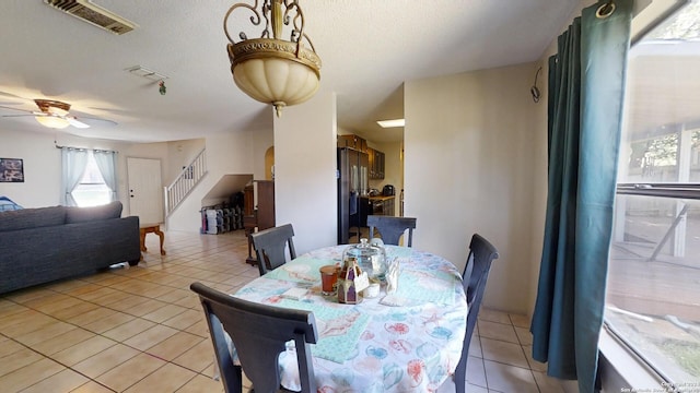 tiled dining room with ceiling fan, a textured ceiling, and plenty of natural light