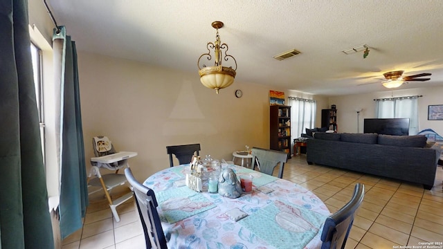 tiled dining space featuring a textured ceiling and ceiling fan