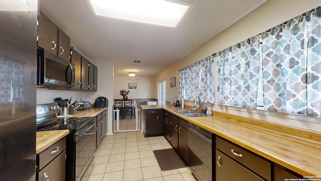 kitchen featuring sink, butcher block counters, dark brown cabinets, stainless steel appliances, and light tile patterned floors