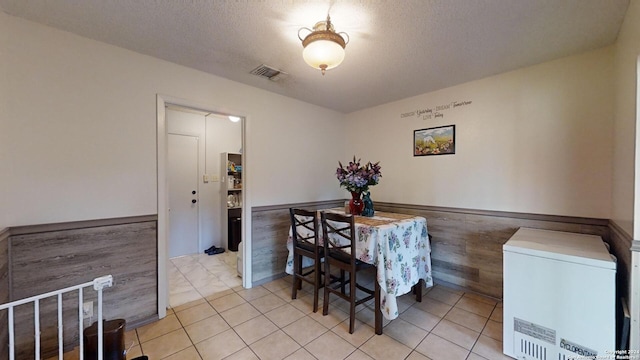 tiled dining area with wood walls and a textured ceiling