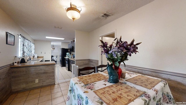 tiled dining area with a textured ceiling and sink