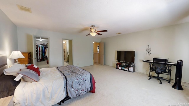 carpeted bedroom with a walk in closet, a closet, and ceiling fan