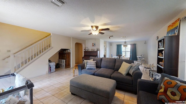 tiled living room with a textured ceiling and ceiling fan with notable chandelier