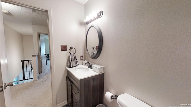 bathroom with toilet, a textured ceiling, and vanity