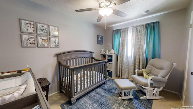 bedroom with a nursery area, a textured ceiling, carpet flooring, and ceiling fan