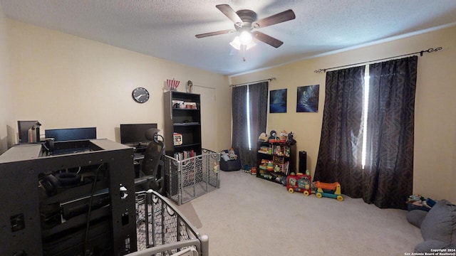 office area with a textured ceiling, carpet, and ceiling fan