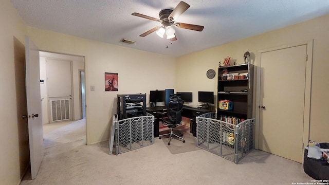 carpeted home office featuring a textured ceiling and ceiling fan