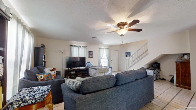 tiled living room with a textured ceiling and ceiling fan