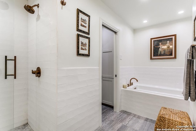 bathroom with independent shower and bath and wood-type flooring