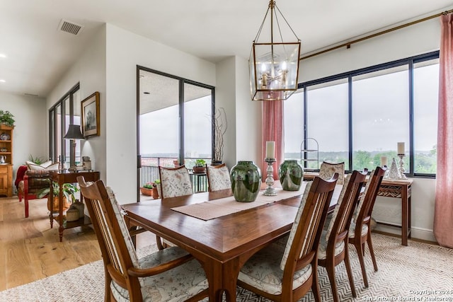 dining room with light hardwood / wood-style flooring and an inviting chandelier