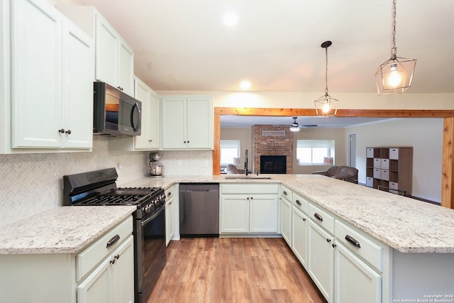 kitchen featuring appliances with stainless steel finishes, sink, light wood-type flooring, hanging light fixtures, and white cabinetry