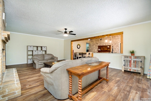 living room with ornamental molding, a textured ceiling, hardwood / wood-style flooring, and ceiling fan