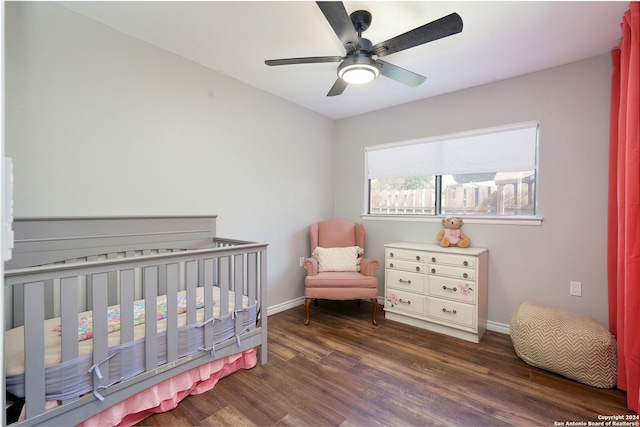 bedroom featuring ceiling fan, dark hardwood / wood-style floors, and a nursery area