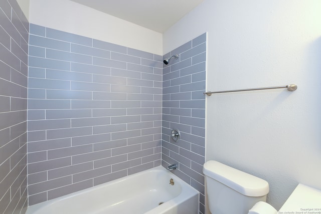 bathroom with tiled shower / bath combo and toilet