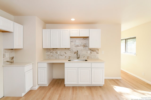 kitchen with decorative backsplash, sink, light wood-type flooring, and white cabinets