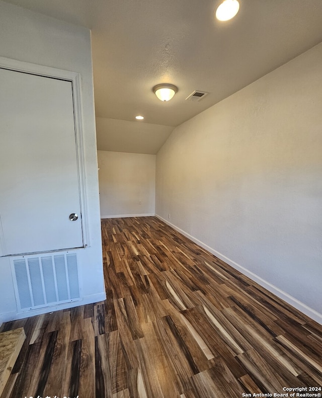 unfurnished room with vaulted ceiling, wood finished floors, visible vents, and baseboards