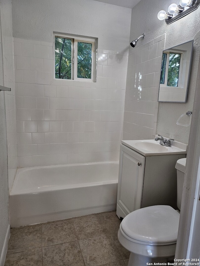 bathroom with toilet, shower / washtub combination, vanity, and a textured wall