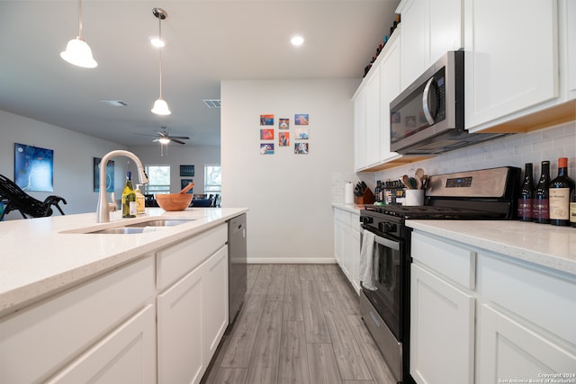 kitchen featuring stainless steel appliances, sink, light wood-type flooring, white cabinetry, and ceiling fan