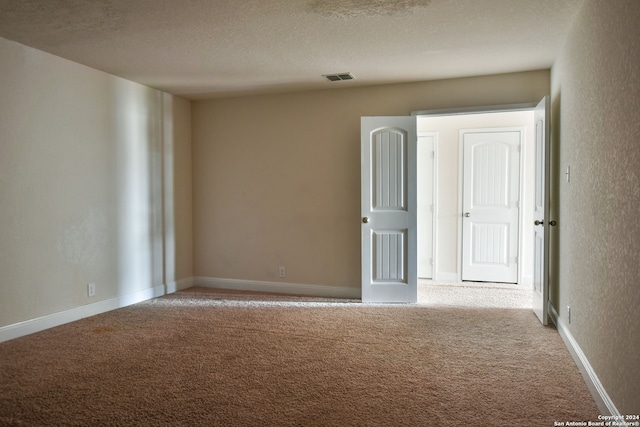 unfurnished room with light carpet and a textured ceiling