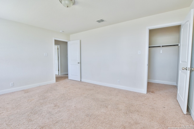 unfurnished bedroom featuring light carpet and a closet