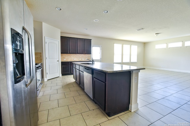 kitchen with tasteful backsplash, sink, an island with sink, stainless steel appliances, and dark brown cabinetry