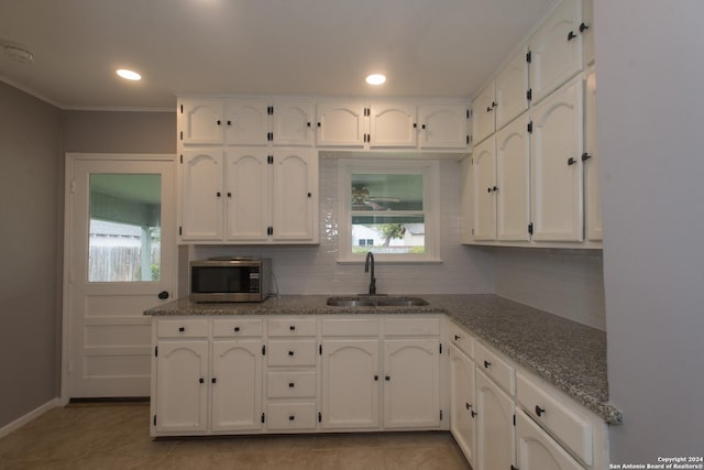 2407 W Mistletoe Ave, San Antonio, TX 78228 - kitchen featuring stainless steel microwave, a sink, white cabinets, tasteful backsplash, and stone countertops