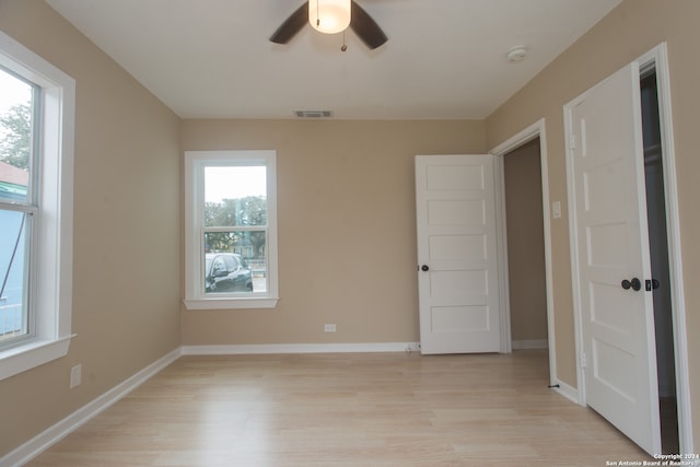 empty room featuring light hardwood / wood-style floors, a healthy amount of sunlight, and ceiling fan