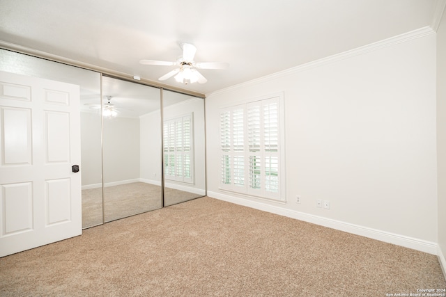 unfurnished bedroom with crown molding, light carpet, a closet, and ceiling fan