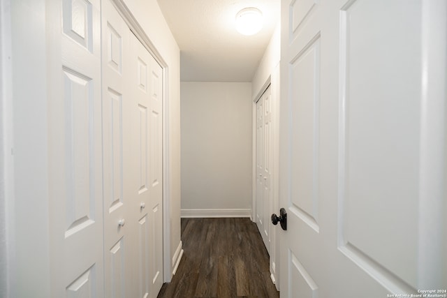 hallway with a textured ceiling and dark hardwood / wood-style flooring