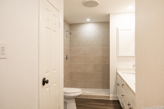 bathroom with vanity, tiled shower, hardwood / wood-style flooring, and toilet