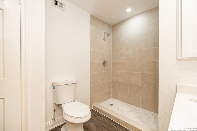 bathroom featuring vanity, toilet, wood-type flooring, and tiled shower