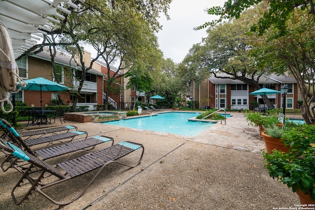 view of swimming pool featuring a patio and a hot tub