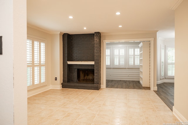 unfurnished living room featuring ornamental molding, a brick fireplace, and light hardwood / wood-style floors