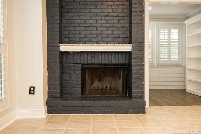 interior details with ornamental molding, hardwood / wood-style flooring, and a brick fireplace